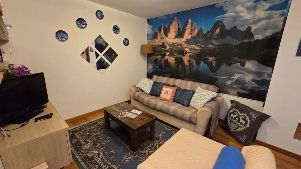 Dimora Alpina Dolomiti Cadore في Vodo Cadore: غرفة معيشة مع أريكة وتلفزيون