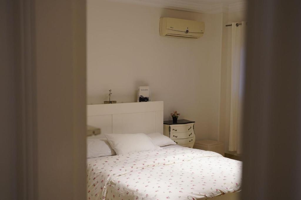 a bedroom with a white bed and a dresser at Garden Home in Sheikh Zayed