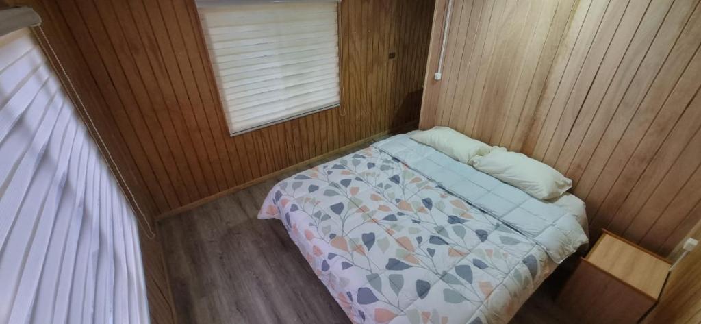a small bedroom with a bed and a window at Cabaña interior en el centro de llanquihue in Llanquihue