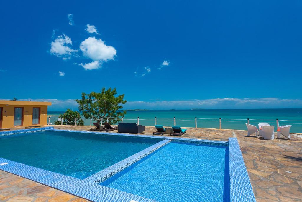 - une piscine avec des chaises et l'océan en arrière-plan dans l'établissement Golden Tulip Zanzibar Resort, à Zanzibar City