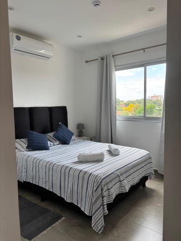 Un dormitorio con una cama con almohadas azules y una ventana. en TR Recoleta, en Asunción
