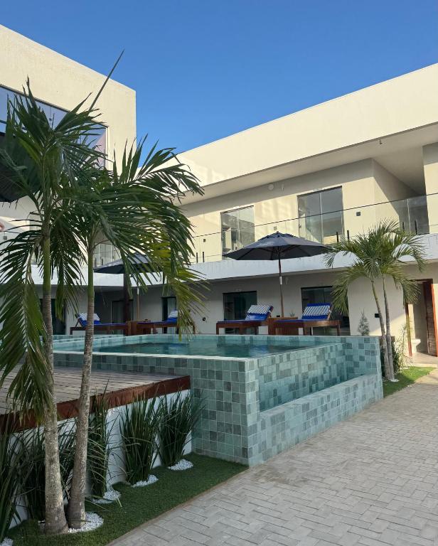 a swimming pool in front of a building with palm trees at Vila Eco Barra AP 209 in Barra Grande