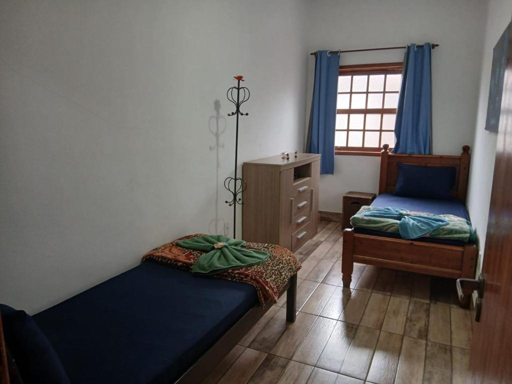 1 Schlafzimmer mit 2 Betten, einer Kommode und einem Fenster in der Unterkunft Casa próxima ao Centro em Tiradentes - MG in Tiradentes