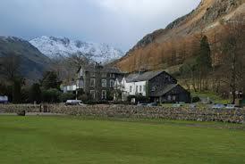 a house in the middle of a green field at The Old Dungeon Ghyll Hotel in Great Langdale