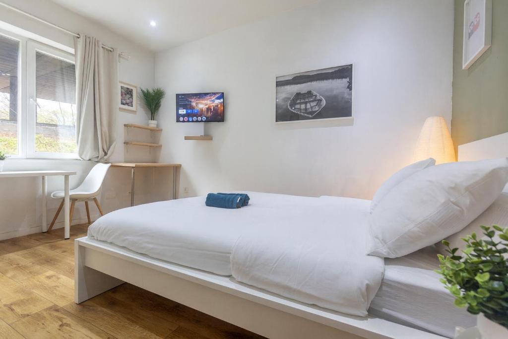 98 Apparthotel - Botanique 3 في لييج: غرفة نوم بيضاء مع سرير ومكتب