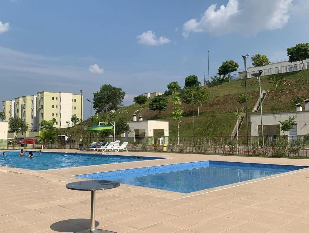 a swimming pool with two stools in front of a building at Apt na Amazônia in Manaus