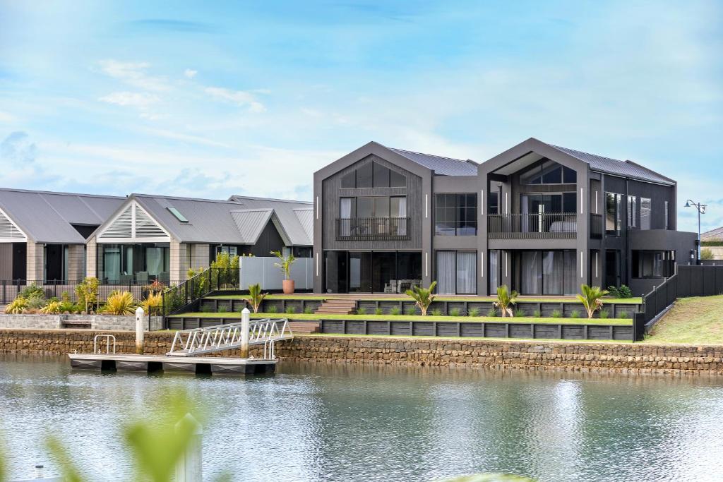 a house on the shore of a body of water at Luxury Beach Retreat - Mountain Views & Boat Jetty in Whitianga