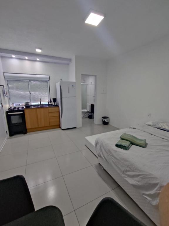 Loft Serra Gaúcha-Bem estar no coração de Nova Petrópolis في نوفا بتروبوليس: غرفة بسرير ومطبخ مع ثلاجة