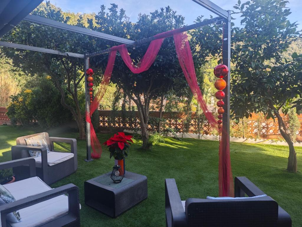 een tuinhuisje met stoelen en bloemen in een tuin bij INSPIRA MAISON Montaña y Mar in Teià