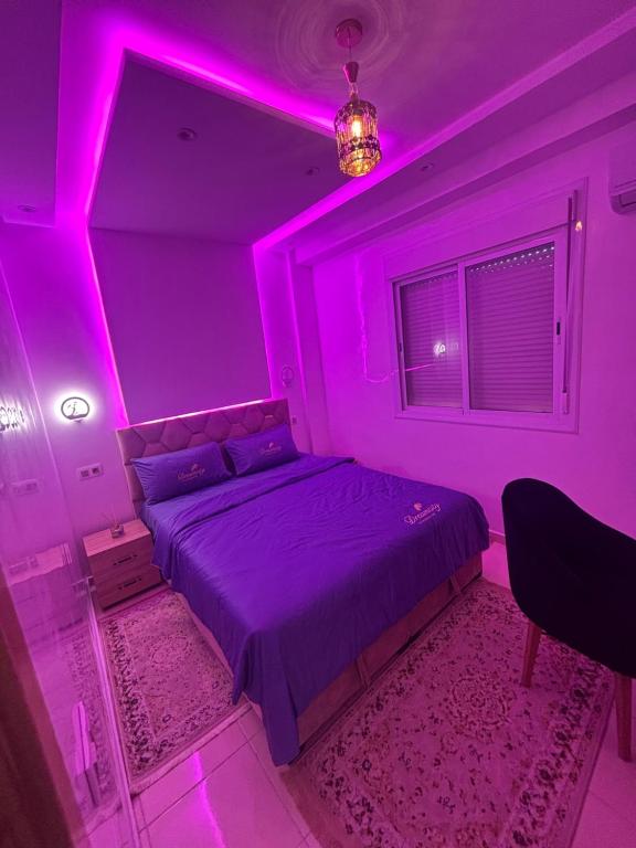 a purple bedroom with a bed with a pink lighting at Appartement traditionnel très moderne in Marrakech