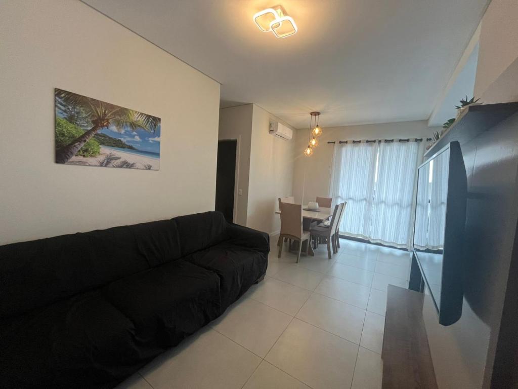 a living room with a black couch and a table at Queridinho da praia de palmas in Governador Celso Ramos