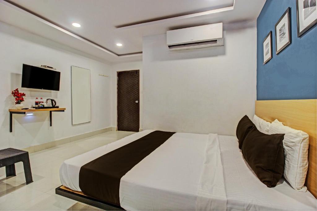 a bedroom with a large bed and a tv at Super Hotel O Qualia Miyapur in Hyderabad