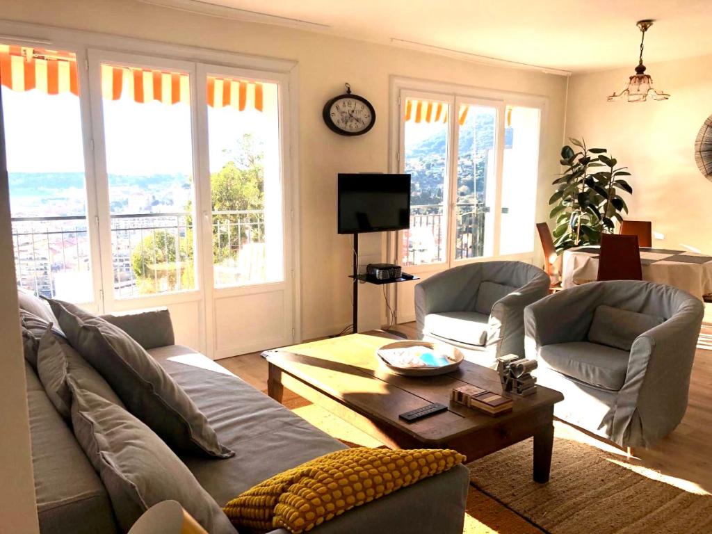 een woonkamer met een bank en een tafel bij Appartement spacieux à 10 minutes de la plage, vue mer in Menton