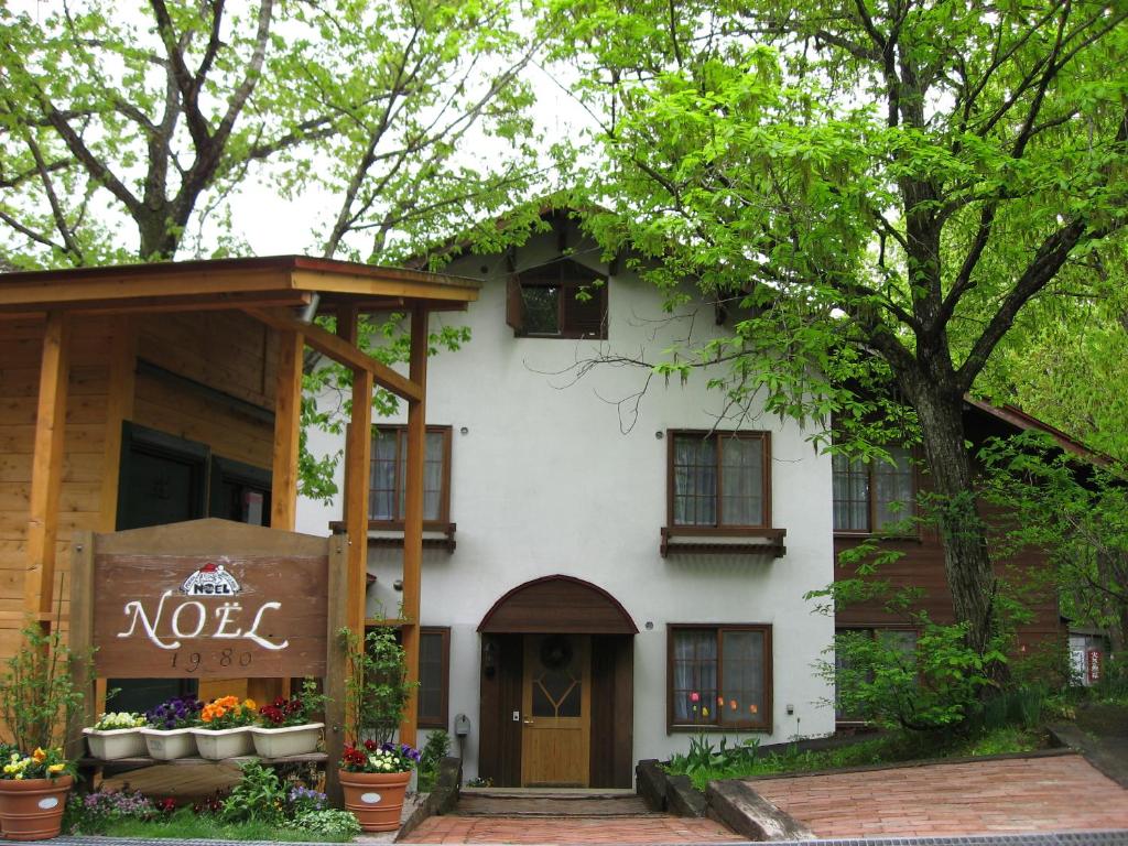 a white house with a sign that says noel on it at Pension Noel in Kaminoyama