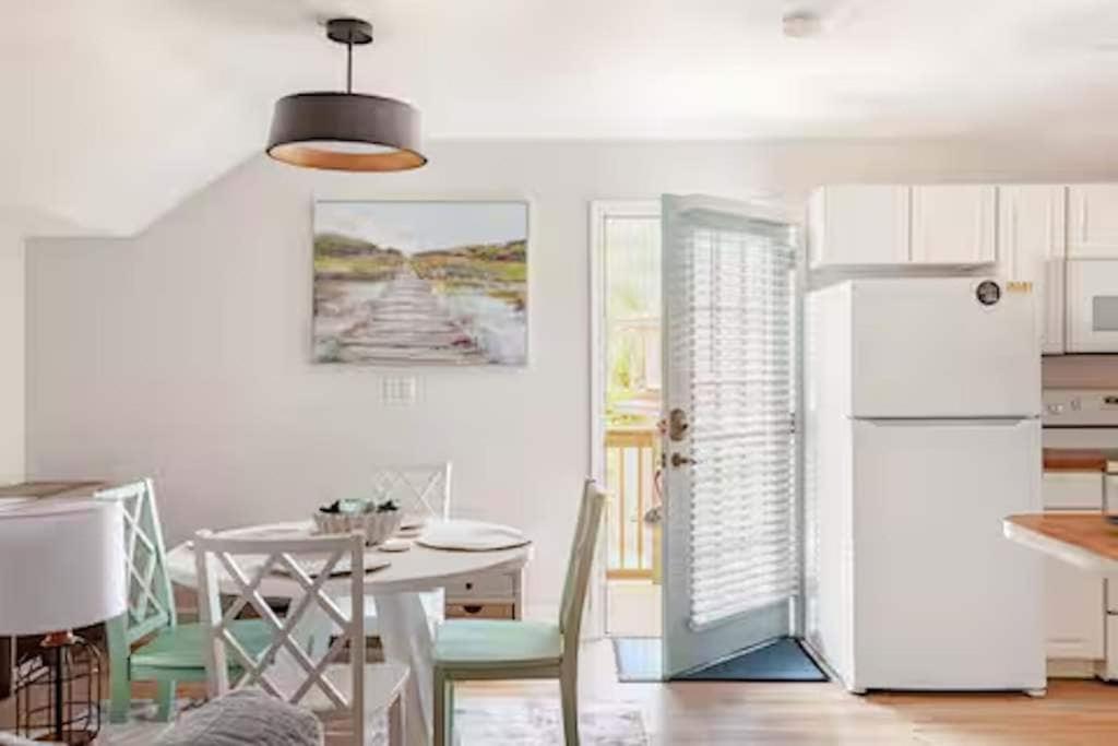 a kitchen with a table and a white refrigerator at Sandy Pines Perch - Your Indian River Dock Life Base Camp in Sebastian