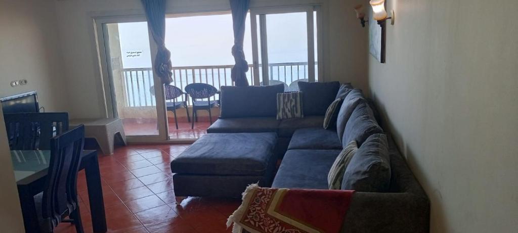 a living room with a blue couch and a balcony at Pyramids Porto Sokhna Hotel Apartments in Ain Sokhna