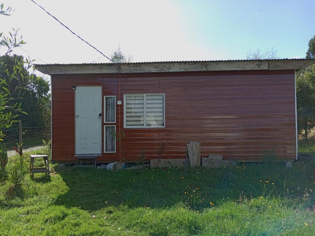 una piccola casa rossa con una porta bianca di Cabaña carmen velasquez a Calbuco