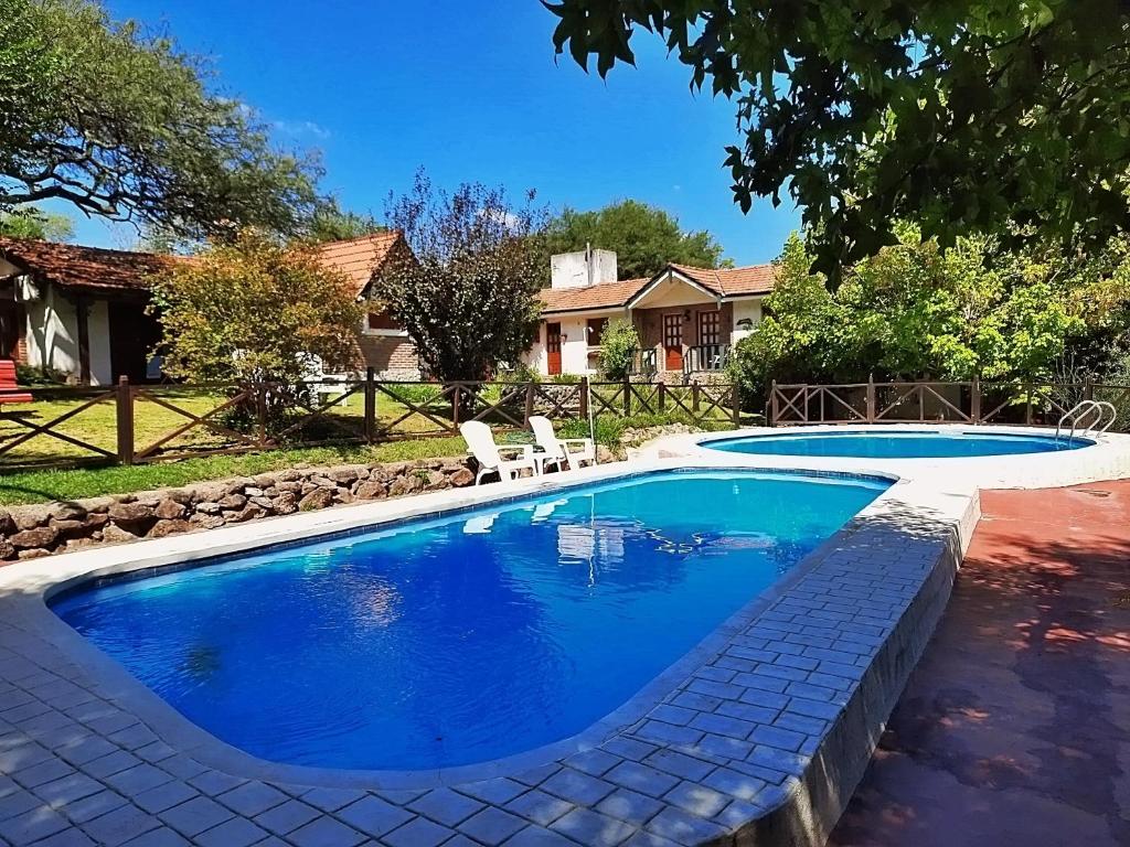 a swimming pool with two chairs in a yard at Cabañas Lorelei in Villa General Belgrano