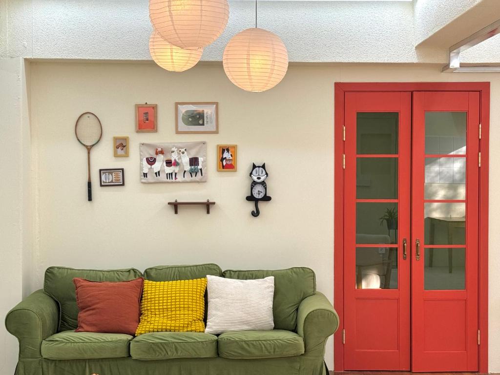 a green couch in a living room with a red door at The FLOW HOUSE in Suwon