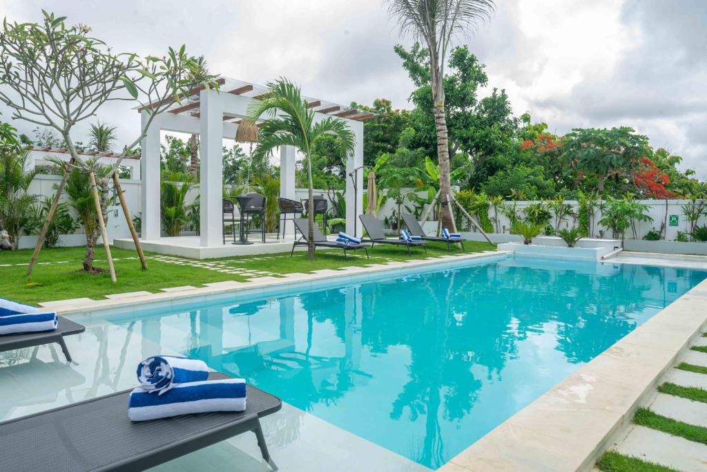 乌鲁瓦图Gandum Villa Complex - Luxury Boutique Stay Uluwatu的度假村的泳池，池水湛蓝，棕榈树摇曳。