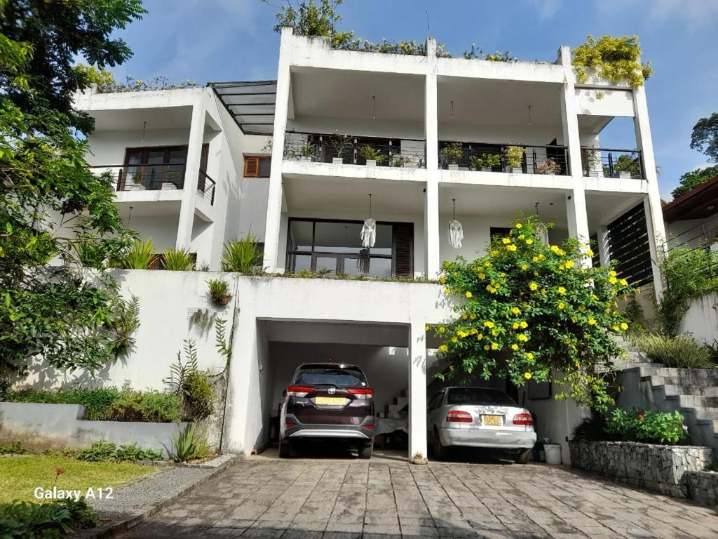 un edificio blanco con dos coches aparcados en él en Pinnacle Life, en Matale