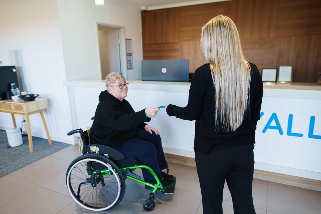 a woman standing next to a man in a wheelchair at MainStay Suites Whyalla in Whyalla