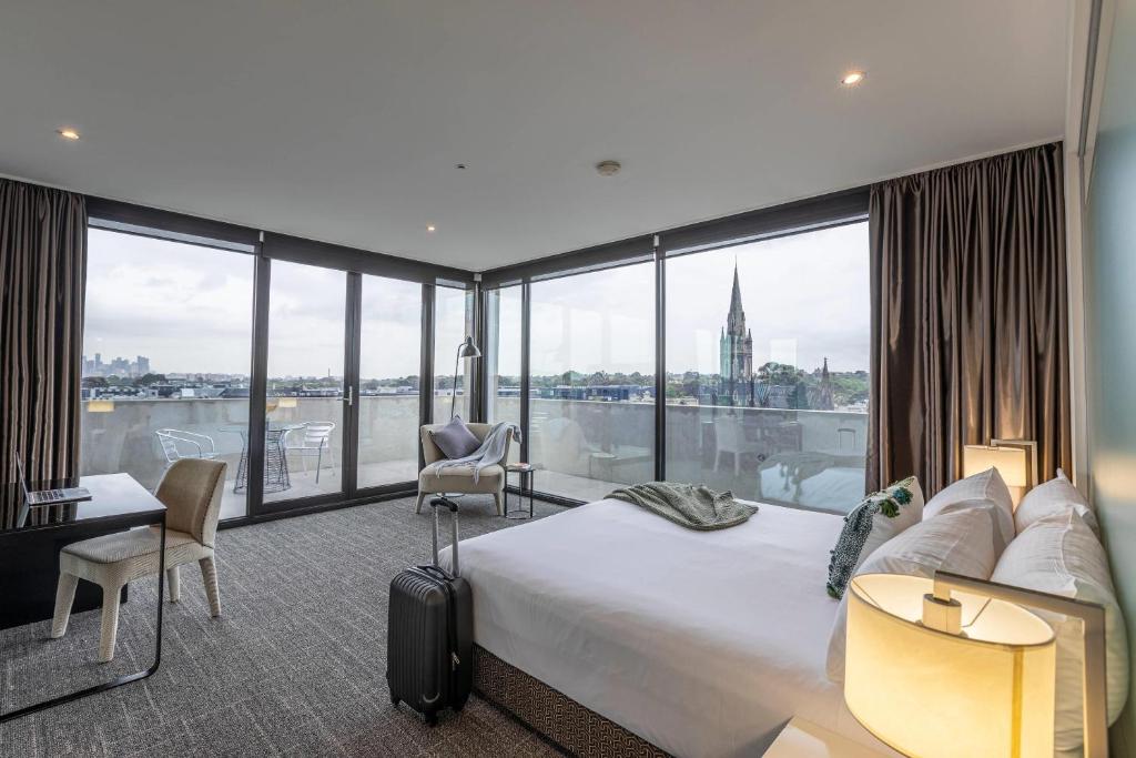 ホーソンにあるMainStay Suites Hawthornのベッドと大きな窓があるホテルの部屋