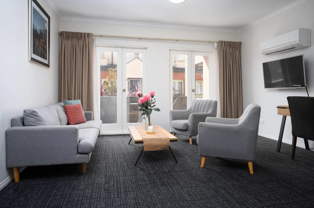 a living room with a couch and chairs and a tv at MainStay Suites Kew in Melbourne