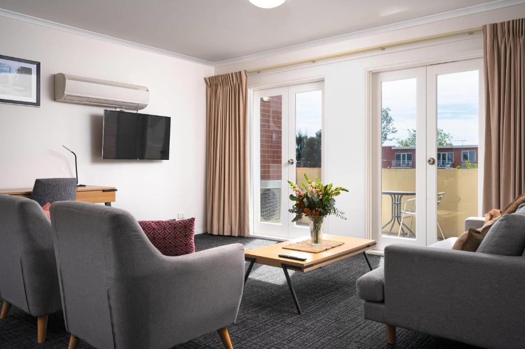 a living room with a couch and chairs and a tv at MainStay Suites Kew in Melbourne