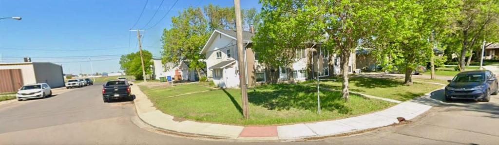 a street with cars parked in front of a house at Joyful Home Regina in Regina