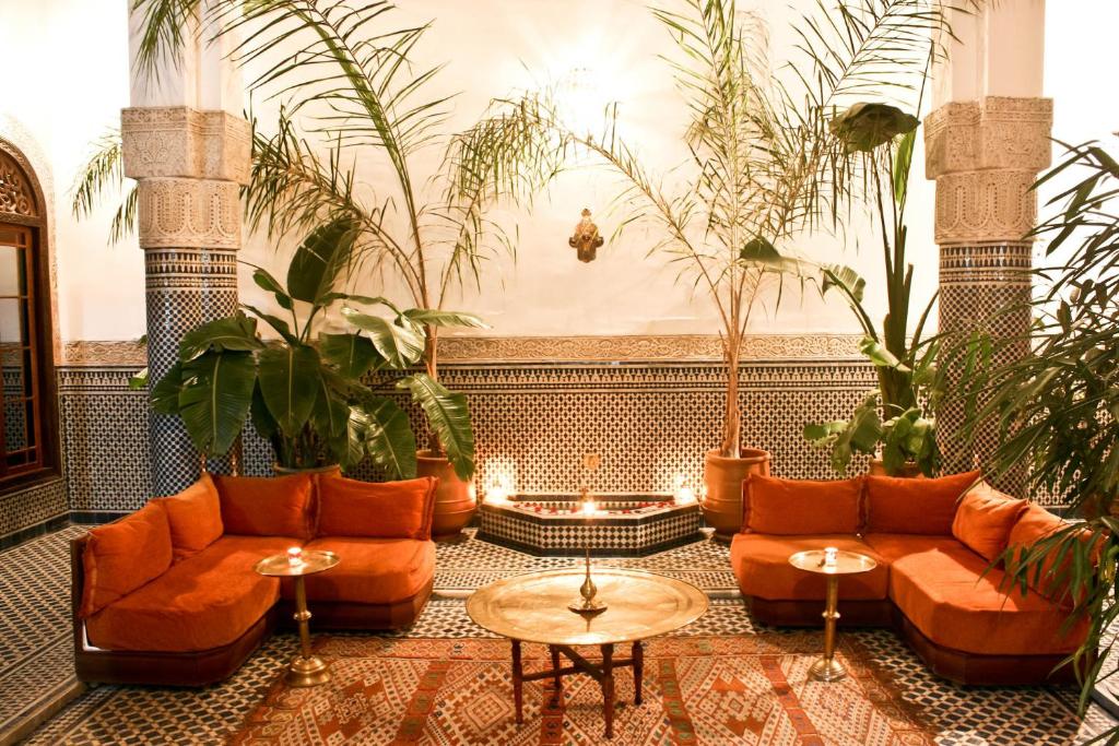 un soggiorno con mobili arancioni e piante di Riad Tayba a Fes