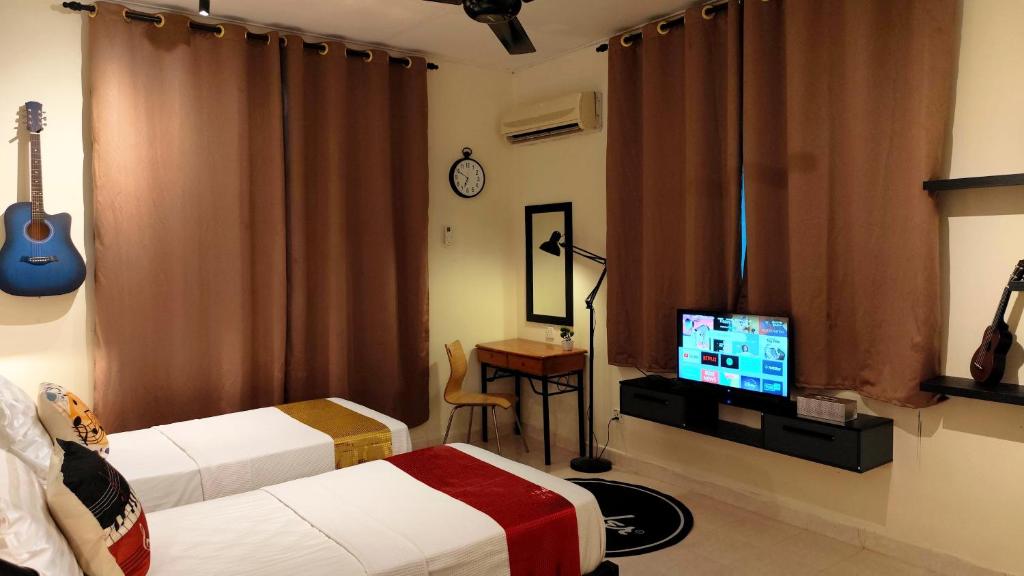 a bedroom with two beds and a television and a guitar at Bayside & Beach Inn Langkawi in Pulau Langkawi