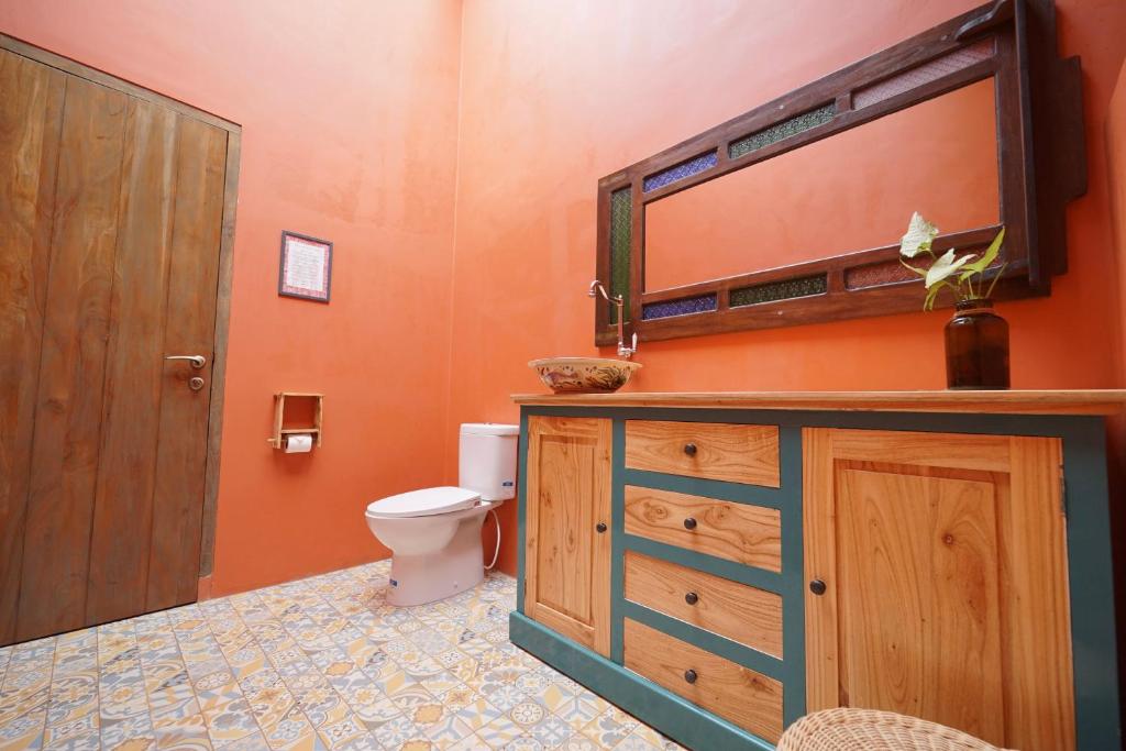 a bathroom with a toilet and a wooden cabinet at Amador by Suasana Villa in Jarakan