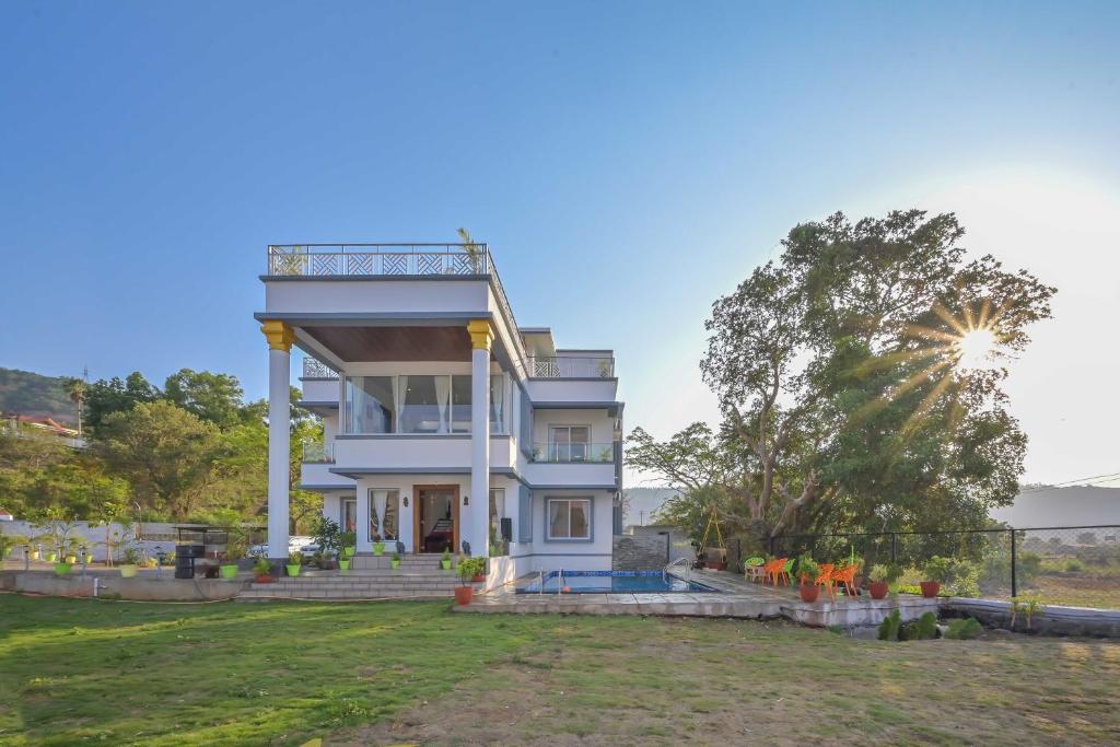 Villa With Turf & Indoor Games في Malavli: بيت ابيض كبير وامامه شجرة