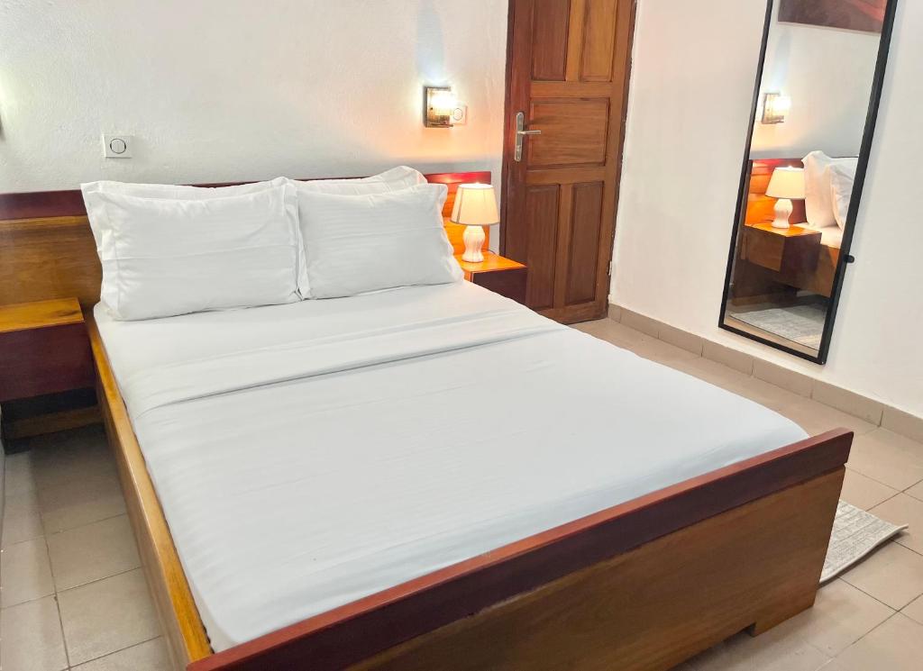 a bed with white sheets and pillows in a room at Yaoundé Daniella house in Yaoundé
