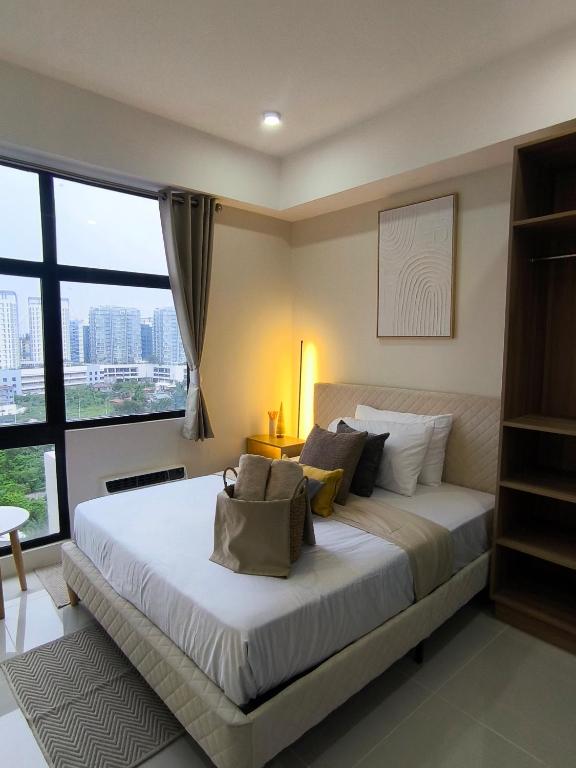 a bedroom with a large bed with a large window at BH UrbanSky Condo in Mactan
