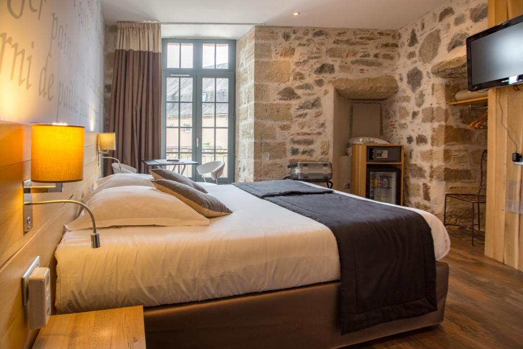 a bedroom with a large bed and a tv at Hotel Le Turenne in Beaulieu-sur-Dordogne