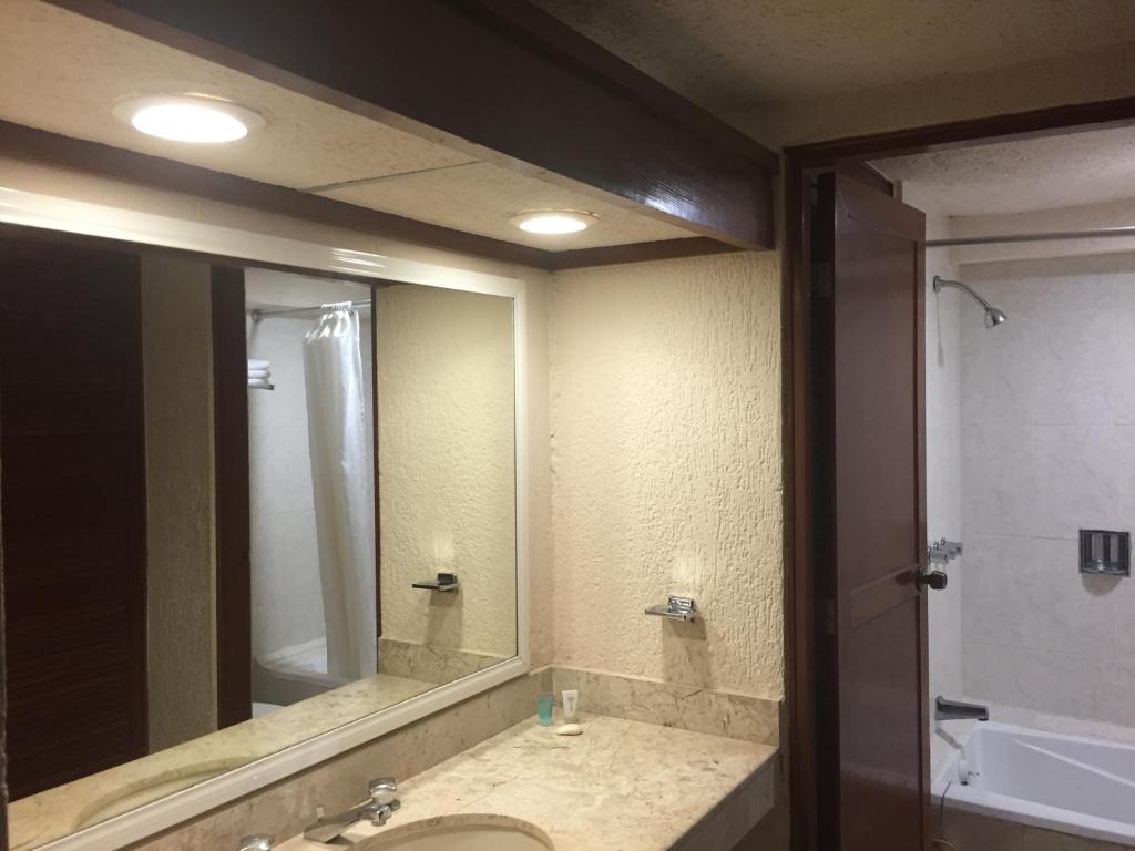 baño con lavabo y espejo grande en Hacienda del Mar Resort Condominio 205, en Cancún