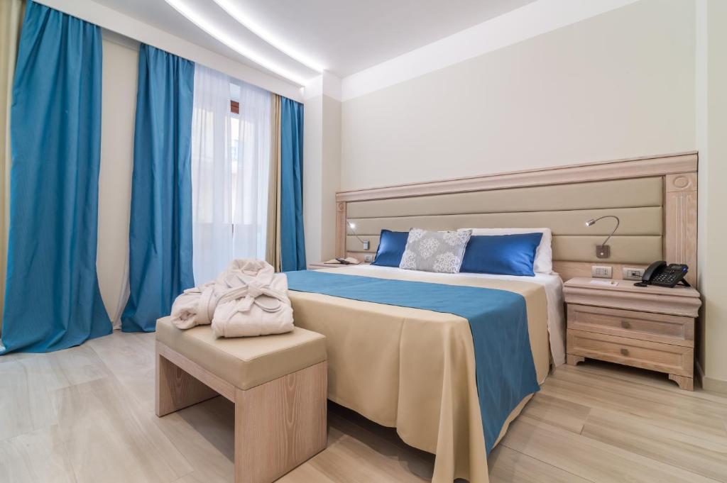 a bedroom with a large bed and blue curtains at L'Ambasciata Hotel de Charme in Cagliari