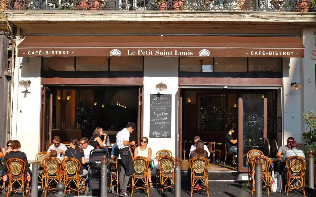 people sitting at tables in front of a restaurant at Hôtel Maison Saint Louis - Vieux Port in Marseille