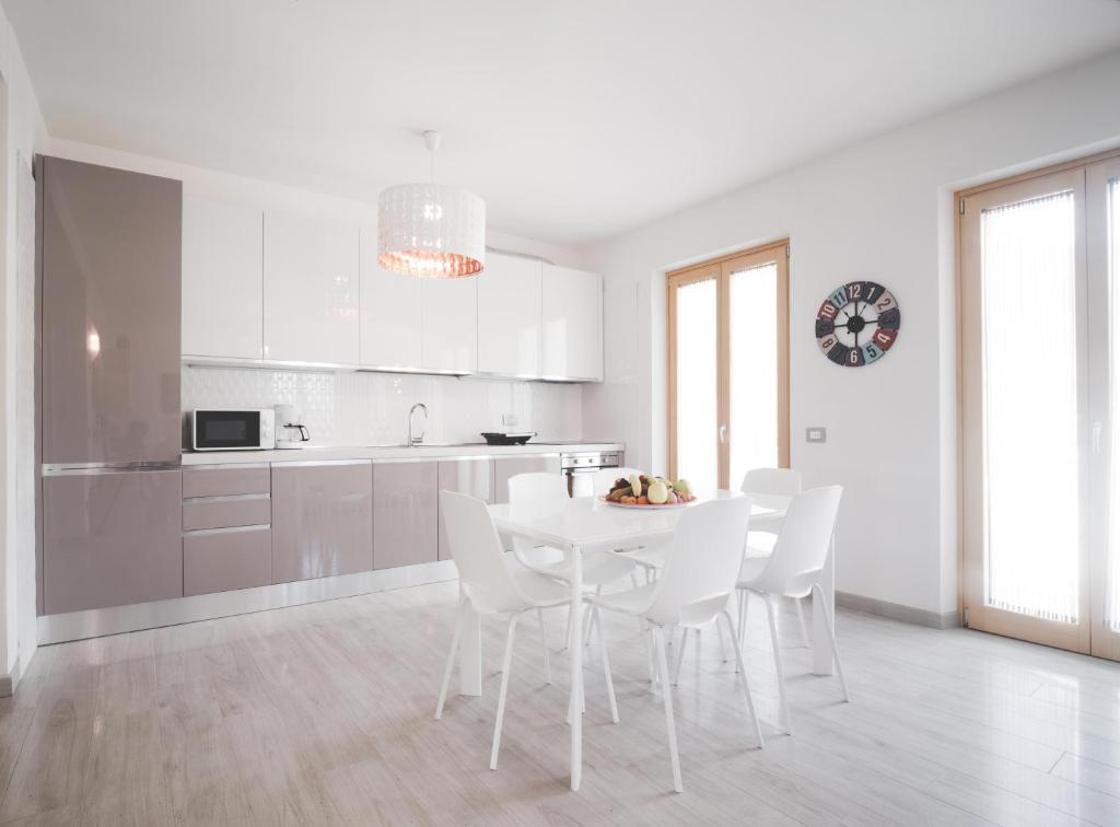 cocina blanca con mesa blanca y sillas blancas en Appartamenti Ora e Peler, en Riva del Garda