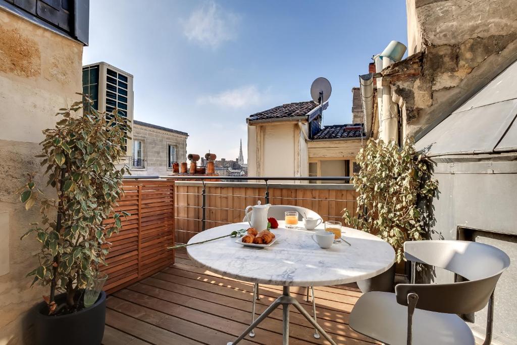 un pequeño balcón con una mesa y sillas blancas en Appartements Place Gambetta - YBH, en Burdeos