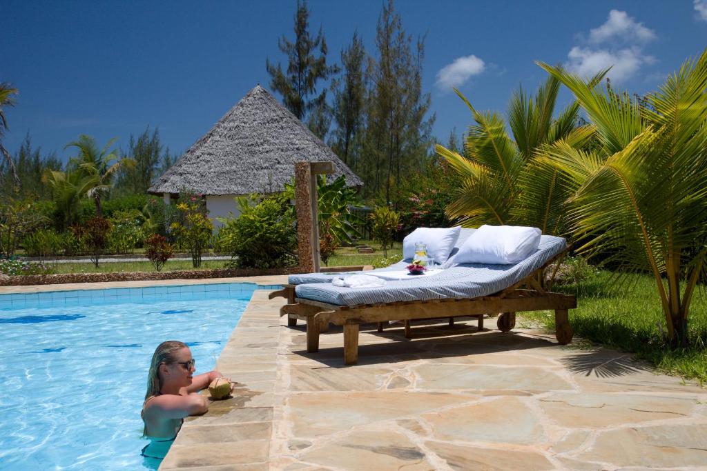 a little girl in the water in a swimming pool at Sheba Cottages - Diani Beach in Diani Beach