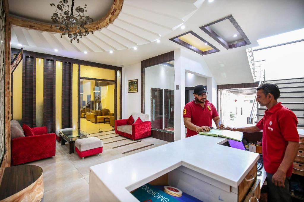 due uomini in piedi in una stanza con un tavolo di Hotel O by OYO MM Yellowuds ad Amritsar