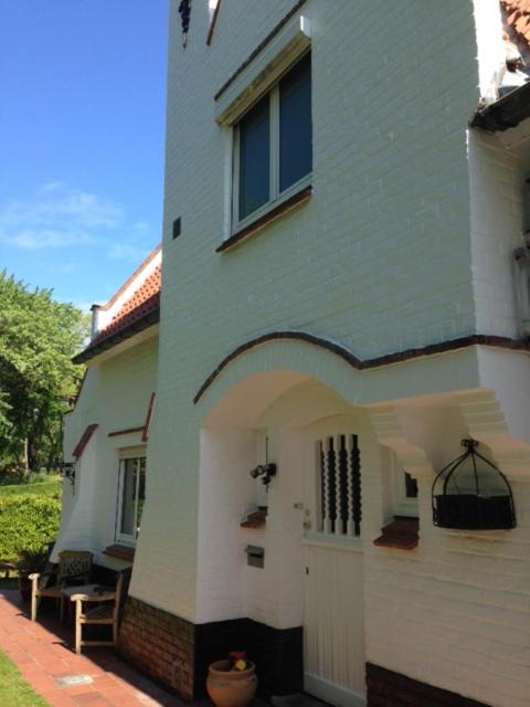 a white building with a door and a window at Villa DM in De Haan