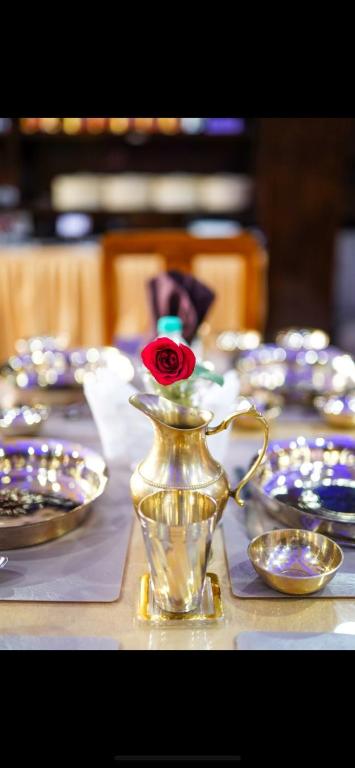 a table with plates and a vase with a rose on it at Retreat Hotel Queen in Darjeeling