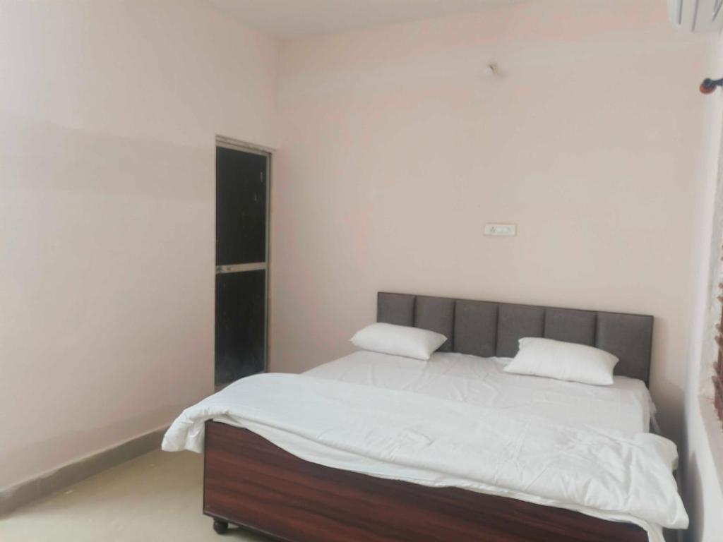 a bedroom with a bed with white sheets and pillows at Hotel O Green Villa in Bilāspur