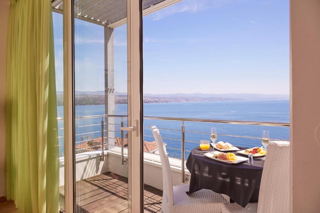 a table with food on a balcony with a view of the ocean at ASTORIA Designhotel Opatija in Opatija