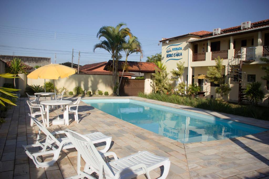 une terrasse avec une table, des chaises et une piscine dans l'établissement Pousada Berro D'Água, à Cananéia
