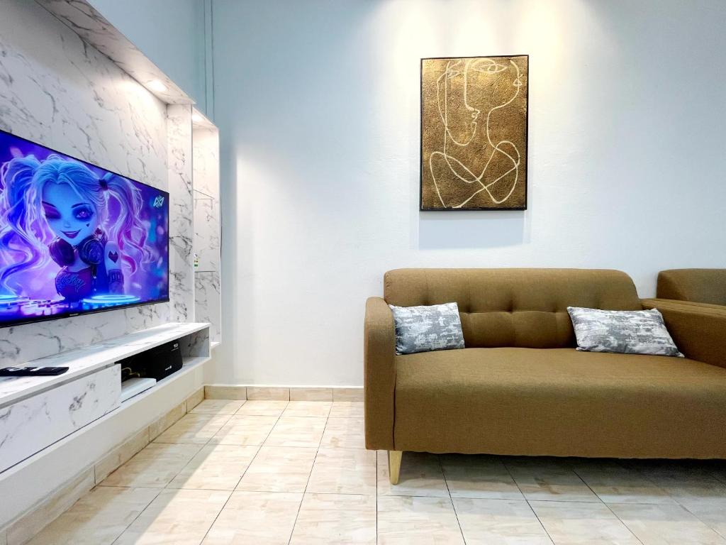 #SE Cozy&Warm 3Bedroom HomeStay 10PAX by S&T Homez في سِريمبان: غرفة معيشة مع أريكة وتلفزيون بشاشة مسطحة